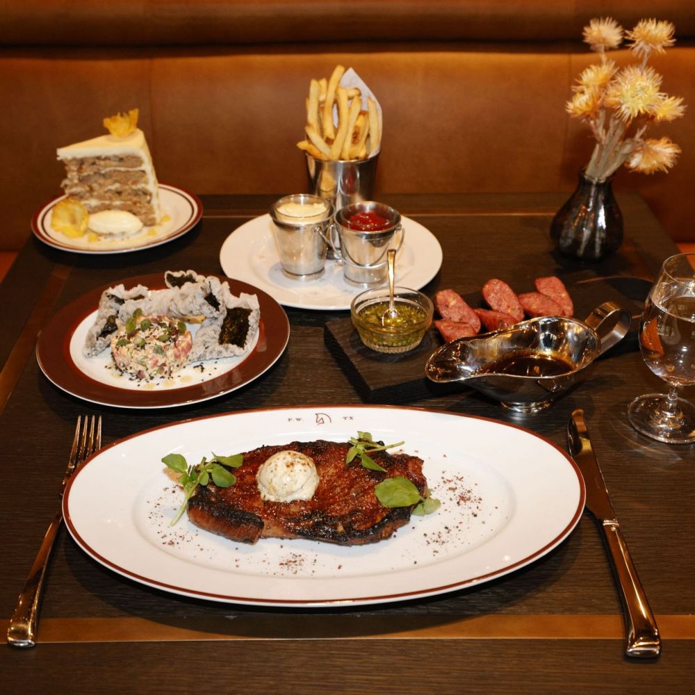 Texas Broil, foreground, Tuna Tartare, left, Hummingbird Cake, background left, House Fries, center, and Wagyu  Jalapeño Cheddar Sausages, right, are seen at Bricks and Horses, the restaurant inside Bowie House hotel, Wednesday, Dec. 20, 2023, in Fort Worth.